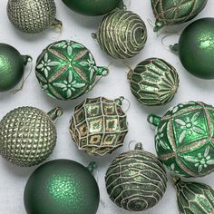 green and gold ornaments are arranged on a white surface