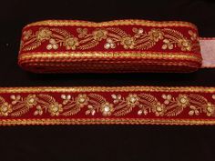 two pieces of red and gold cloth with floral designs on the edges, one is rolled up