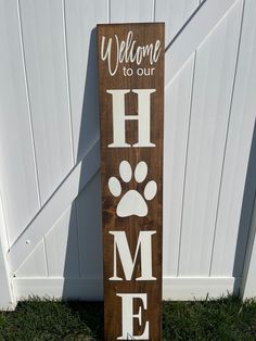 a wooden sign that says welcome to our home with a dog's paw on it