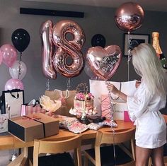 a woman standing in front of a table filled with pink and black balloons