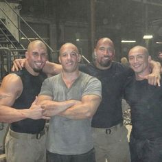 three men are posing for a photo in front of a group of other men with their arms around each other