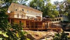 a large house sitting on top of a lush green hillside next to a forest filled with trees