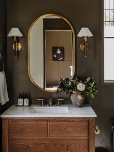 a bathroom with a sink, mirror and flowers on the counter in front of it