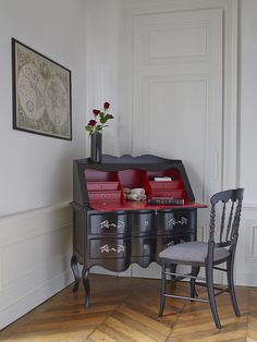 a black desk with drawers and a chair in front of it on top of a hard wood floor