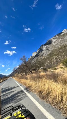 a view from the back of a motorcycle on a road with mountains in the background