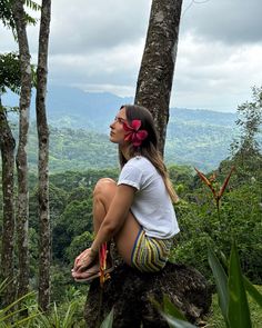 a woman sitting on top of a tree in the forest