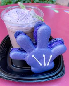 a purple bunny shaped cookie sitting on top of a black plate next to a drink