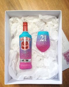 two wine glasses in a box with tissue paper on the bottom and one is pink