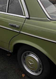 an old green car is parked on the street