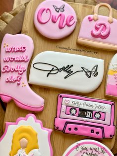 decorated cookies with pink and white designs on a wooden tray next to other cookie items