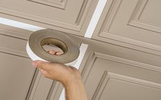 a person holding a roll of tape in front of a door with the handle on it