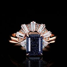 a blue and white diamond ring sitting on top of a black surface with its reflection in the glass