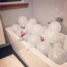 some white balloons in a bathtub filled with little red men and one big white balloon