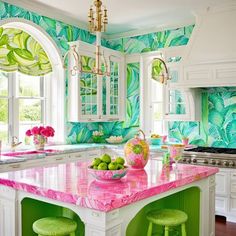 a kitchen with green and pink decor on the counter tops, white cabinets and an island