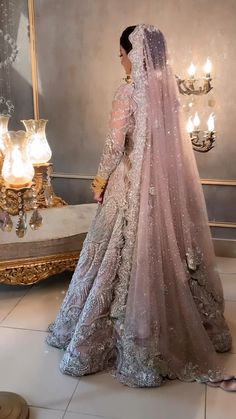 a woman in a wedding dress looking at herself in front of a mirror with candles