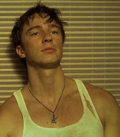 a young man wearing a white tank top with a cross necklace on it's neck