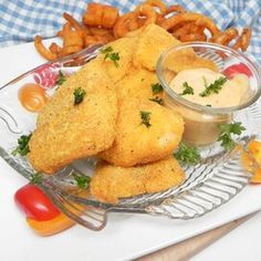 fried fish and fries on a glass plate with dipping sauce in the bowl next to them