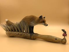 a fake animal is sitting on top of a toothbrush with a small bird perched on it