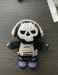 a small crocheted doll with a skull on it's head sitting on a table