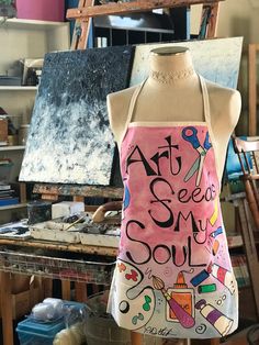 an apron that says art see my soul on it in front of a painting easel