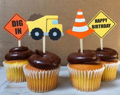 three cupcakes with chocolate frosting and construction signs