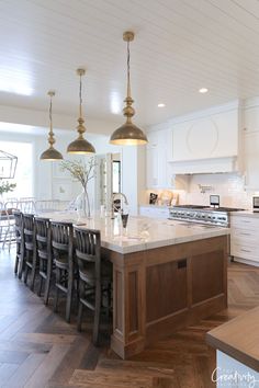 a large kitchen with an island in the middle and two pendant lights hanging from the ceiling