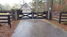 a gated driveway leading to a house in the woods with autumn leaves on the ground