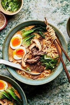 two bowls filled with ramen, mushrooms and eggs on top of a marble table