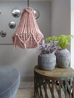 a pink chandelier hanging from a ceiling in a room with potted plants