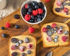 three pieces of toast with berries and powdered sugar on them next to a bowl of raspberries