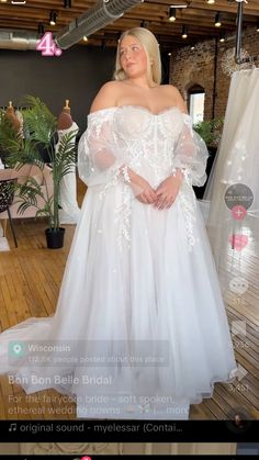 a woman in a white wedding dress standing on a wooden floor with her arms behind her back