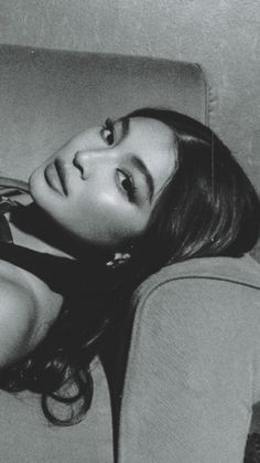 a black and white photo of a woman laying on a couch with her hair in the air