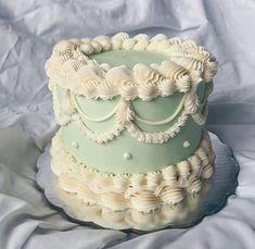 a three tiered cake with white icing on a sheet covered tablecloth,