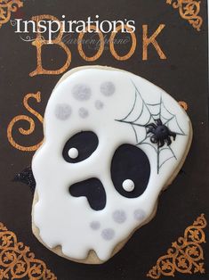 a decorated sugar cookie with black and white icing on it that says, inspirations book spook