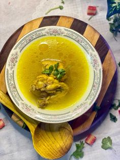 a bowl filled with soup sitting on top of a wooden plate next to a spoon