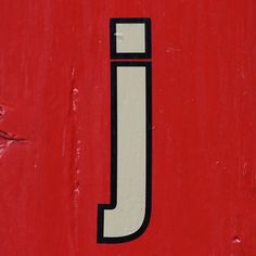 a close up of the letter j on a red wall