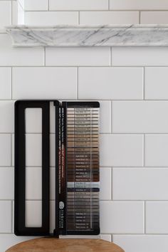 a stack of cassettes sitting on top of a wooden table next to a white tiled wall