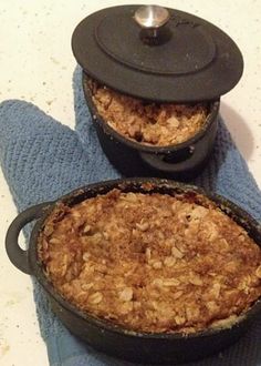 two pans filled with food sitting on top of a blue dish towel next to each other