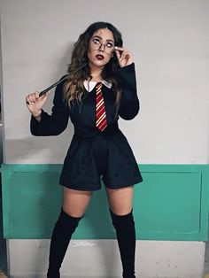 a woman dressed as harry potter holding a wand and posing in front of a wall