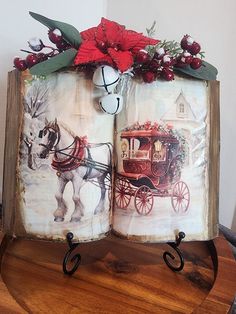 an open book decorated with christmas decorations and horse drawn buggy on top of a wooden table