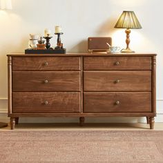 a wooden dresser sitting next to a lamp on top of a rug