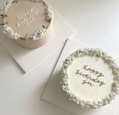 two birthday cakes with white frosting and flowers on them, one is for someone's first birthday