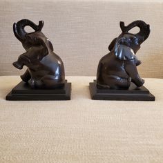 two statues of elephants sitting on top of each other in front of a beige couch