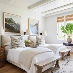 two beds in a bedroom with white linens and pillows on top of each bed