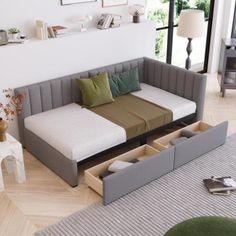 a living room with a couch, bed and storage drawers on the floor in front of it