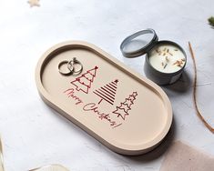 two wedding rings are sitting on a tray next to a candle and some twinklings