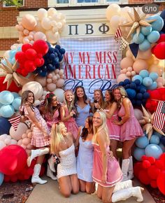 a group of young women standing next to each other in front of an american flag backdrop