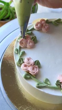 a person is decorating a cake with flowers on the frosting and icing