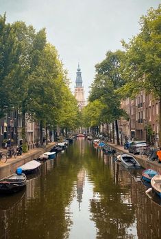 several boats are parked on the side of a canal in front of buildings and trees