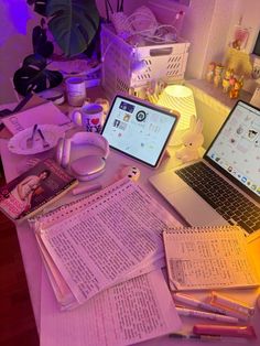 two laptops sitting on top of a desk next to papers and other items in front of them